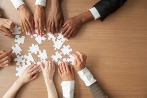 Hands of multi-ethnic business team assembling jigsaw puzzle, top view