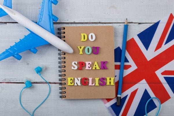 Concept of learning English language – colorful letters with text “Do you speak English”, flag of the UK, airplane, headphones