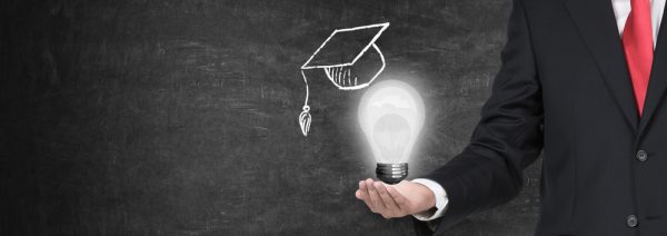 A,Hand,Holding,A,Mortarboard,With,A,Light,Bulb,,Concept